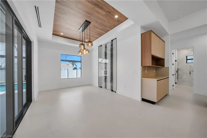 Unfurnished dining area with a wooden tray ceiling, plenty of natural light, and a chandelier