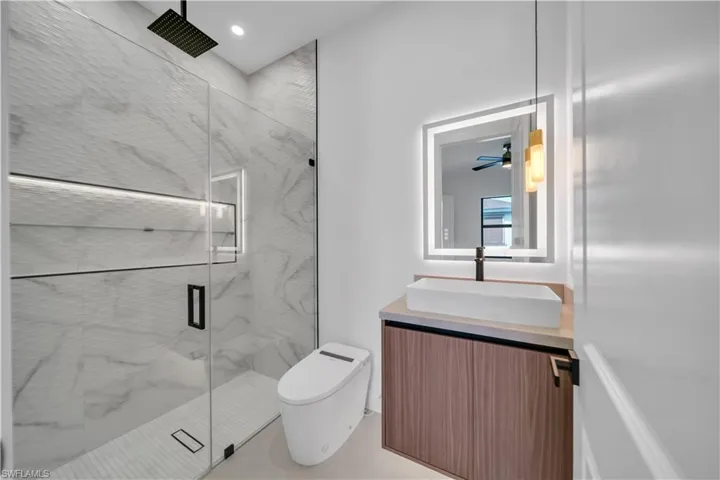Bathroom featuring vanity, a marble finish shower, a ceiling fan, and recessed lighting