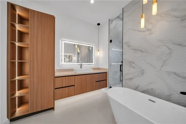 Full bathroom featuring vanity, a freestanding tub, a marble finish shower, and recessed lighting