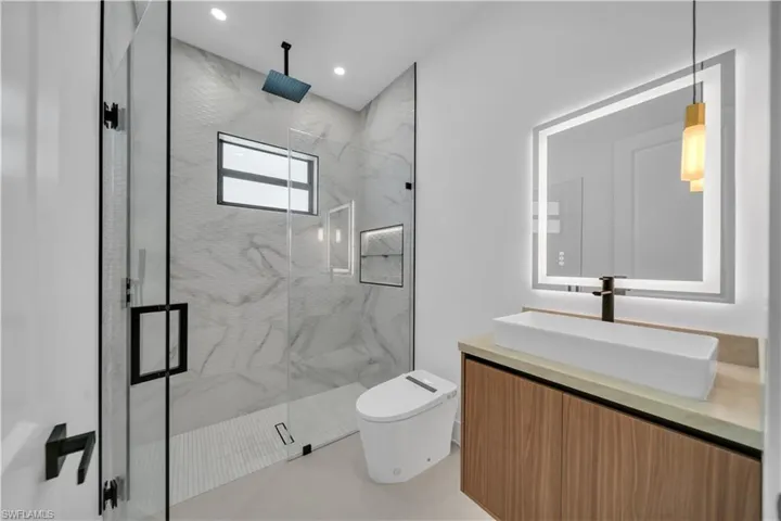 Full bathroom featuring vanity, a marble finish shower, and recessed lighting