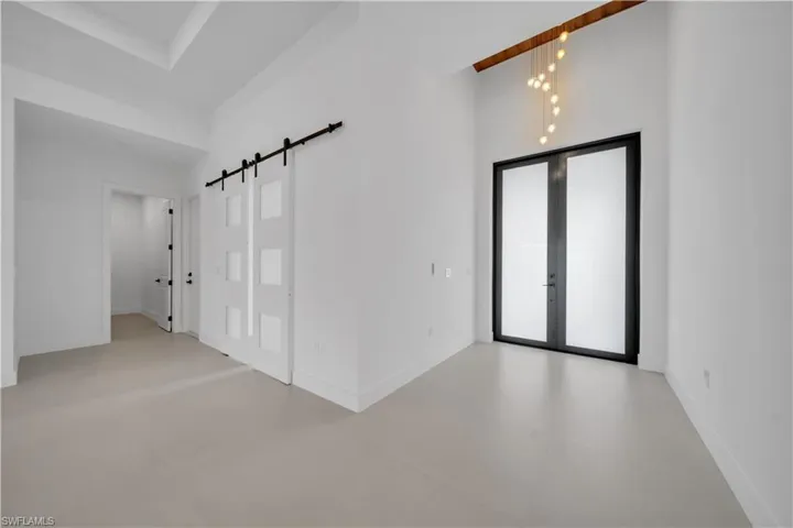 Spare room featuring a barn door, a high ceiling, concrete floors, and french doors