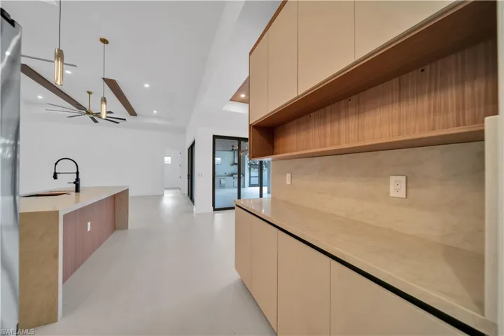 Kitchen featuring open shelves, cream cabinets, recessed lighting, modern cabinets, and light stone counters