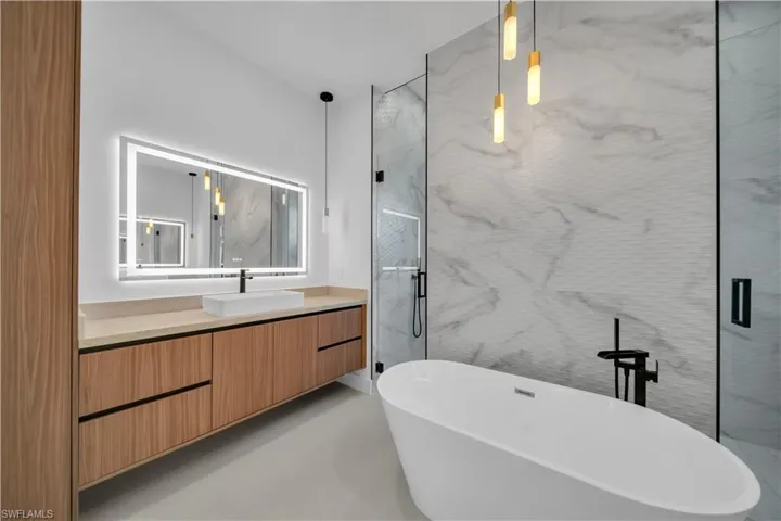 Full bath with vanity, a marble finish shower, and a soaking tub