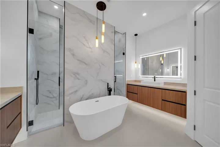 Full bath featuring vanity, a freestanding bath, a marble finish shower, concrete flooring, and recessed lighting