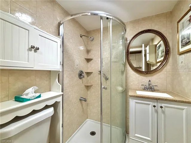 Bathroom featuring tile walls, a shower stall, vanity, and decorative backsplash