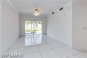 Expansive interior space featuring large format white tile flooring, crown molding, and a ceiling fan