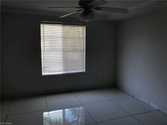 Room featuring a window with horizontal blinds, overhead ceiling fan, crown molding, and large format tile flooring