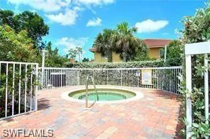 Outdoor spa surrounded by a white metal fence and paver decking