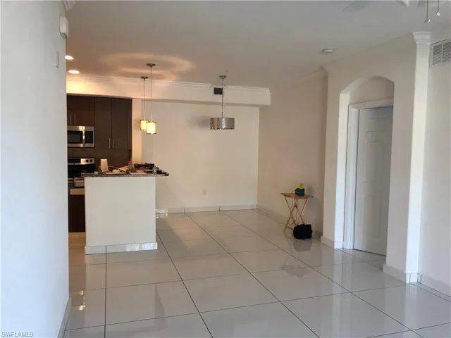 Spacious open-concept living area featuring large format tile flooring, crown molding, and recessed lighting