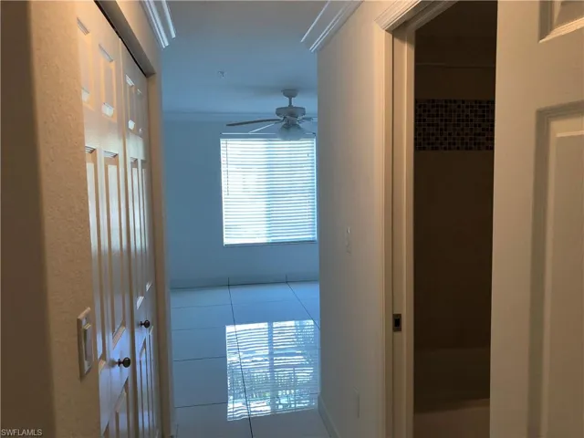 Bright interior space featuring a window with blinds, a ceiling fan, crown molding, and tiled flooring