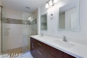 Dual sink vanity with dark wood-finish cabinetry, light-toned countertop, and integrated sinks