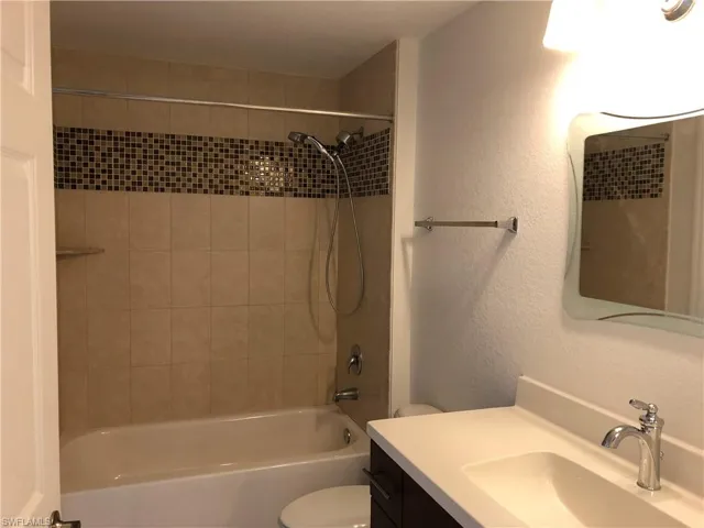 Bathroom featuring a tub and shower combination with tan wall tile and a mosaic accent band