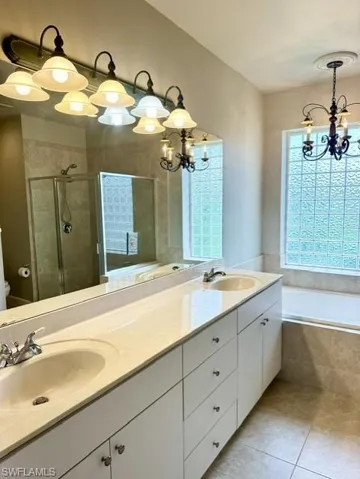 Full bathroom with tile patterned floors, shower with separate bathtub, plenty of natural light, and vanity