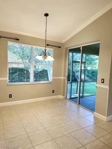 Unfurnished dining area with a wealth of natural light, crown molding, vaulted ceiling, and light tile patterned floors