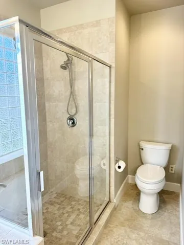 Bathroom featuring tile patterned flooring, toilet, and walk in shower