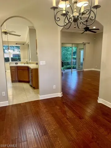 Unfurnished dining area with light tile patterned floors, crown molding, and ceiling fan with notable chandelier
