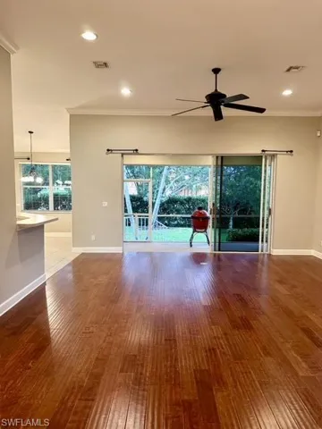 Unfurnished living room featuring a healthy amount of sunlight, wood-type flooring, and ceiling fan