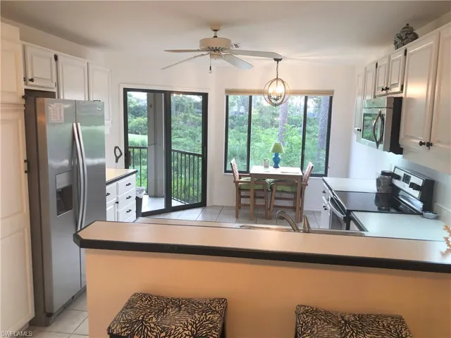 Kitchen featuring light tile patterned flooring, stainless steel appliances, white cabinetry, and a ceiling fan