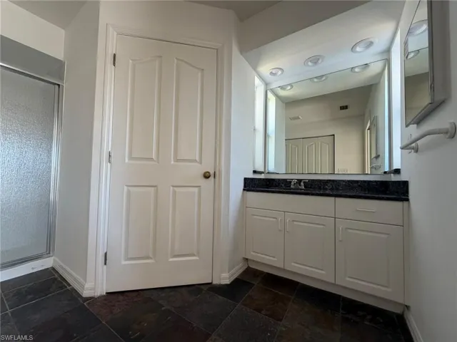 Full bathroom featuring vanity, a stall shower, and stone tile floors