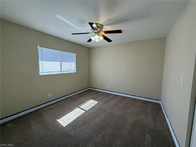 Carpeted empty room featuring a ceiling fan and baseboards