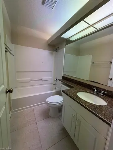 Bathroom featuring bathing tub / shower combination, vanity, a textured ceiling, and light tile patterned floors