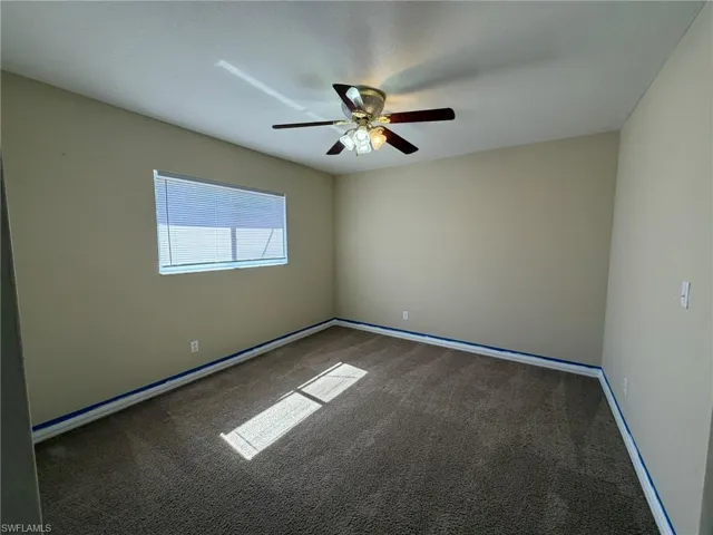 Spare room featuring dark colored carpet and ceiling fan