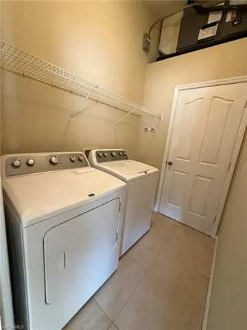 Laundry area with light tile patterned flooring and washing machine and clothes dryer