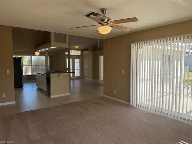 Unfurnished room featuring ceiling fan, light carpet, and french doors