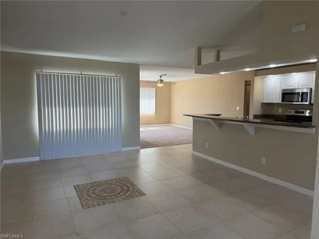 Kitchen with a breakfast bar area, white cabinetry, a ceiling fan, open floor plan, and stainless steel appliances