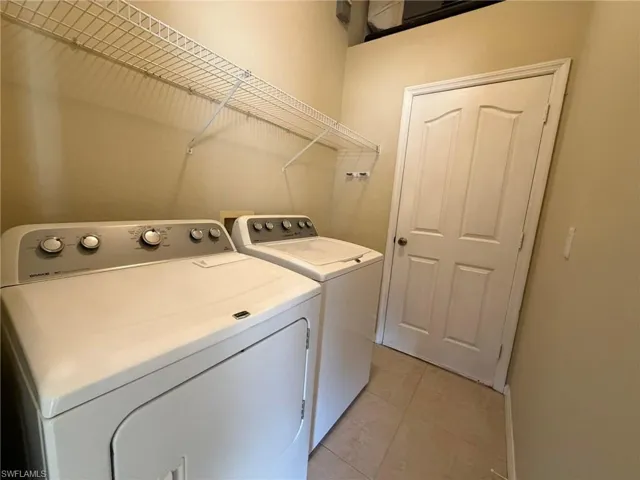 Laundry area with light tile patterned flooring and washer and clothes dryer