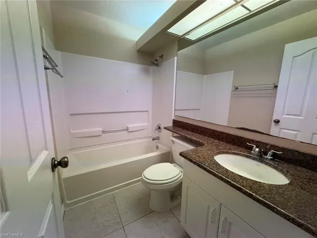 Bathroom with vanity, tub / shower combination, and light tile patterned flooring