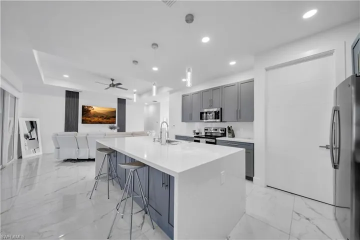 Kitchen featuring gray cabinets, a breakfast bar, light stone countertops, and a spacious island
