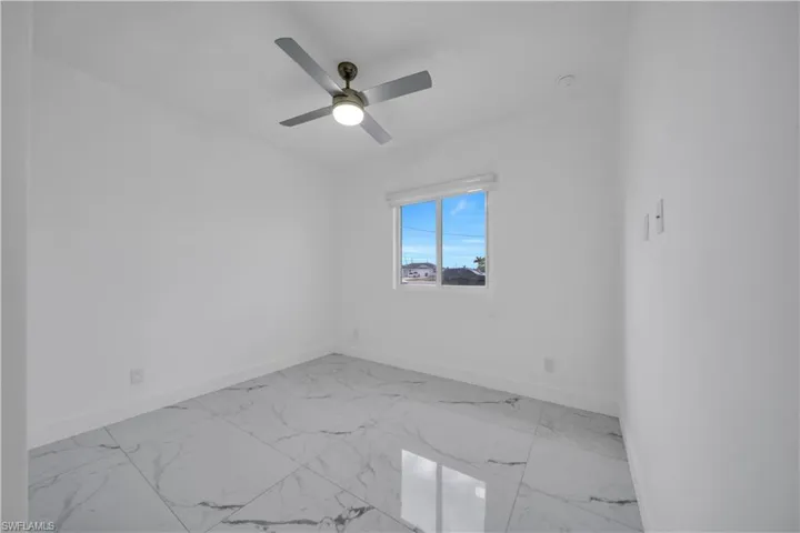 Spare room with light marble finish flooring and ceiling fan