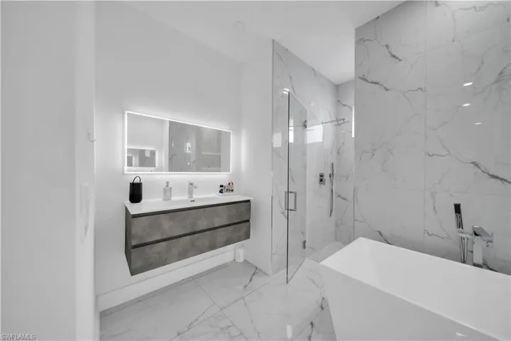 Full bathroom with a marble finish shower, a soaking tub, vanity, and light marble finish floors