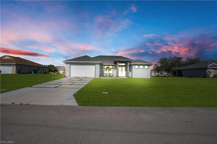 Prairie-style house with a front lawn, driveway, an attached garage, and stucco siding