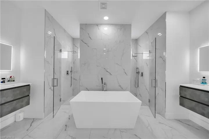 Bathroom with vanity, a marble finish shower, a freestanding bath, recessed lighting, and light marble finish flooring