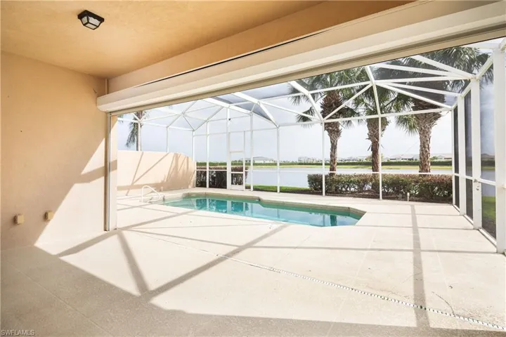 Pool with glass enclosure, a patio area, and a water view