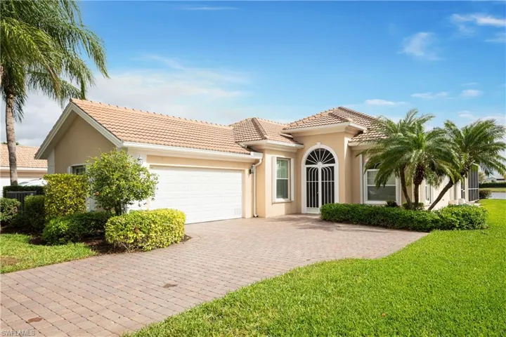 View of front facade with stucco siding, a tiled roof, an attached garage, decorative paver driveway, and a front yard