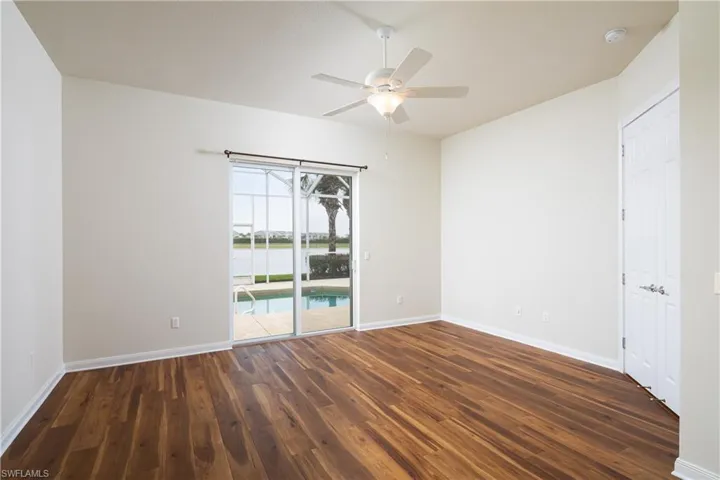 Primary Bedroom with luxury plank flooring, lake view and sliders to pool.