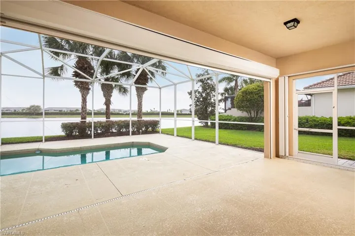 Outdoor pool with a water view, glass enclosure, a yard, and a patio