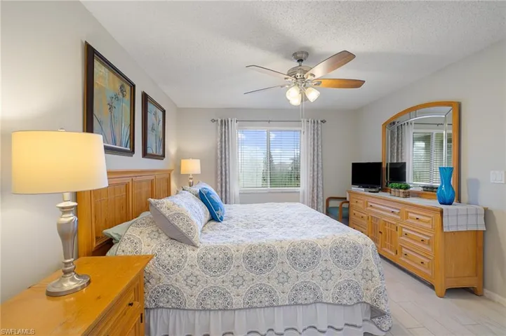 Bedroom with ceiling fan, light hardwood / wood-style flooring, and a textured ceiling