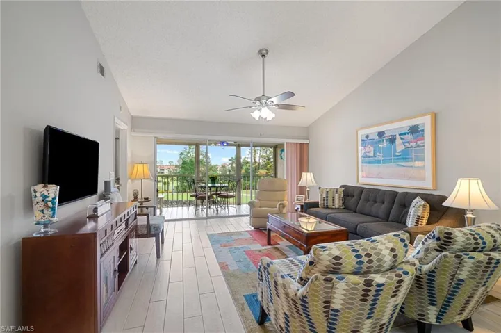 Living room featuring ceiling fan, a textured ceiling, and lofted ceiling