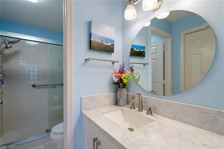 Bathroom featuring a shower with shower door, toilet, and vanity