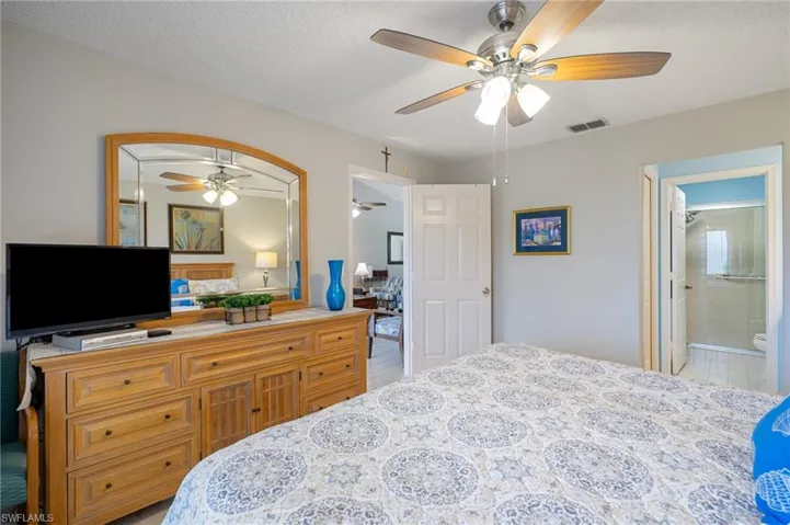 Bedroom with a textured ceiling, connected bathroom, and ceiling fan