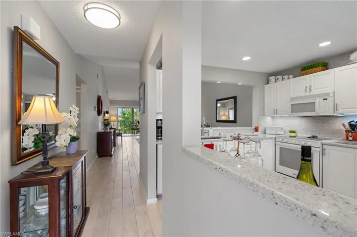 Kitchen featuring white cabinetry, tasteful backsplash, light stone countertops, white appliances, and a textured ceiling