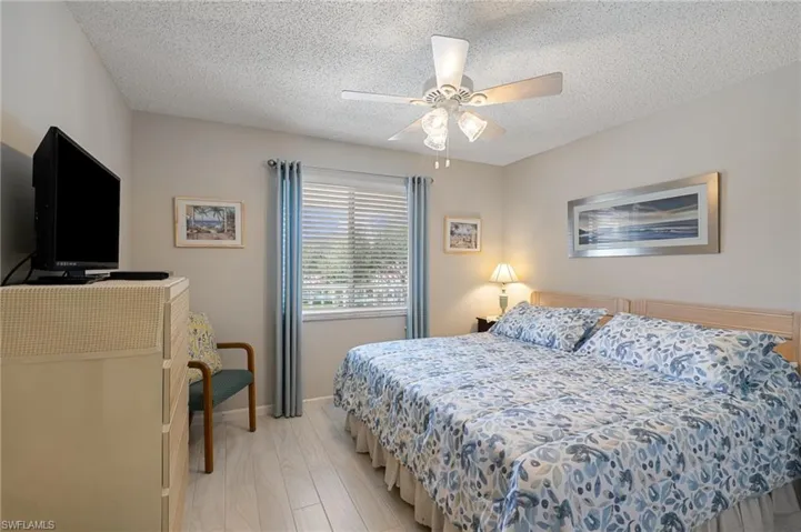 Bedroom featuring light hardwood / wood-style floors, a textured ceiling, and ceiling fan