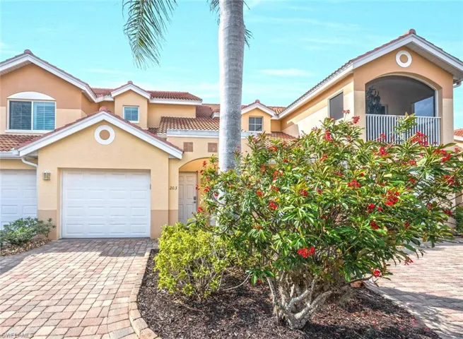 Front View of Charming Carriage Home with Private Home with Private Garage, Tile Roof, & Paver Driveway.