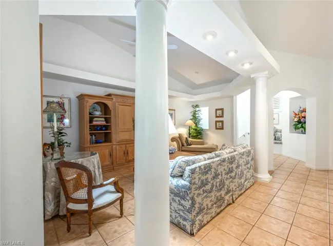 Family Room featuring light tile patterned floors, decorative columns, a raised ceiling, and a ceiling fan
