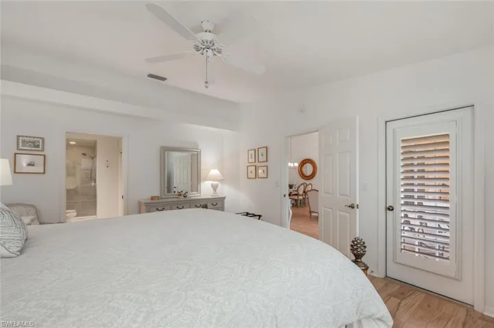 Primary Bedroom featuring ceiling fan, light wood finished wood floors, and en-suite bath with walk in shower.