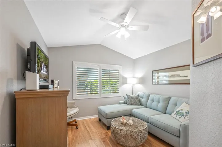 Den with lofted ceiling and ceiling fan